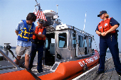 Handcuffed adult male being taken into custody by USCG officers for boating under the influence.